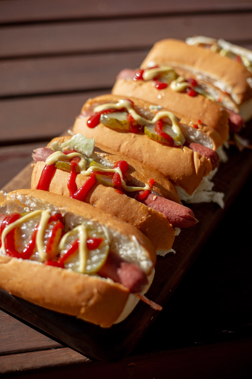 Hot dogs with various condiments on a wooden surface