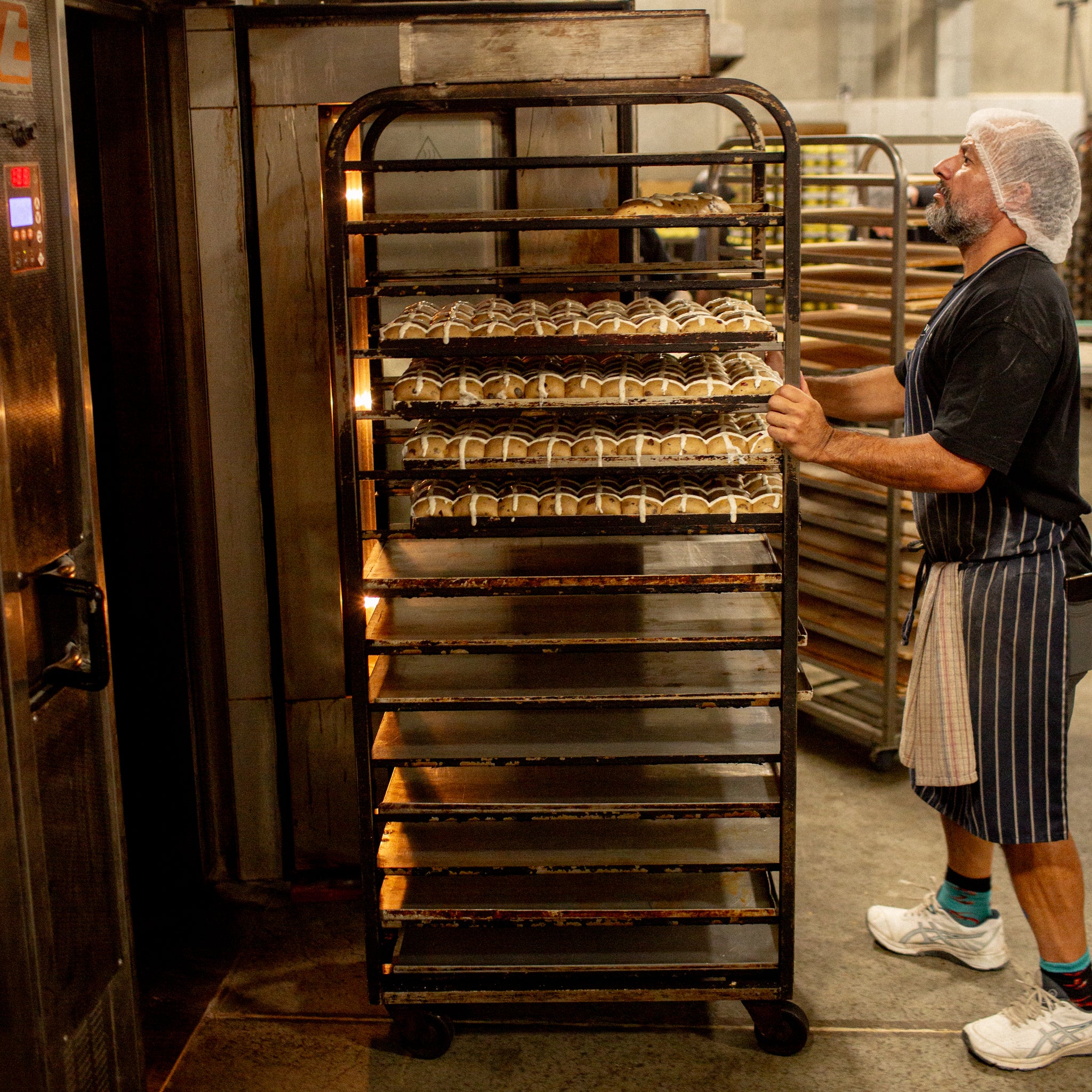 Rolling a rack of Hot Cross Buns into the oven