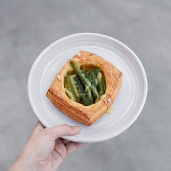 Hand holding a plate with Volare Asparagus Danish sitting on it.
