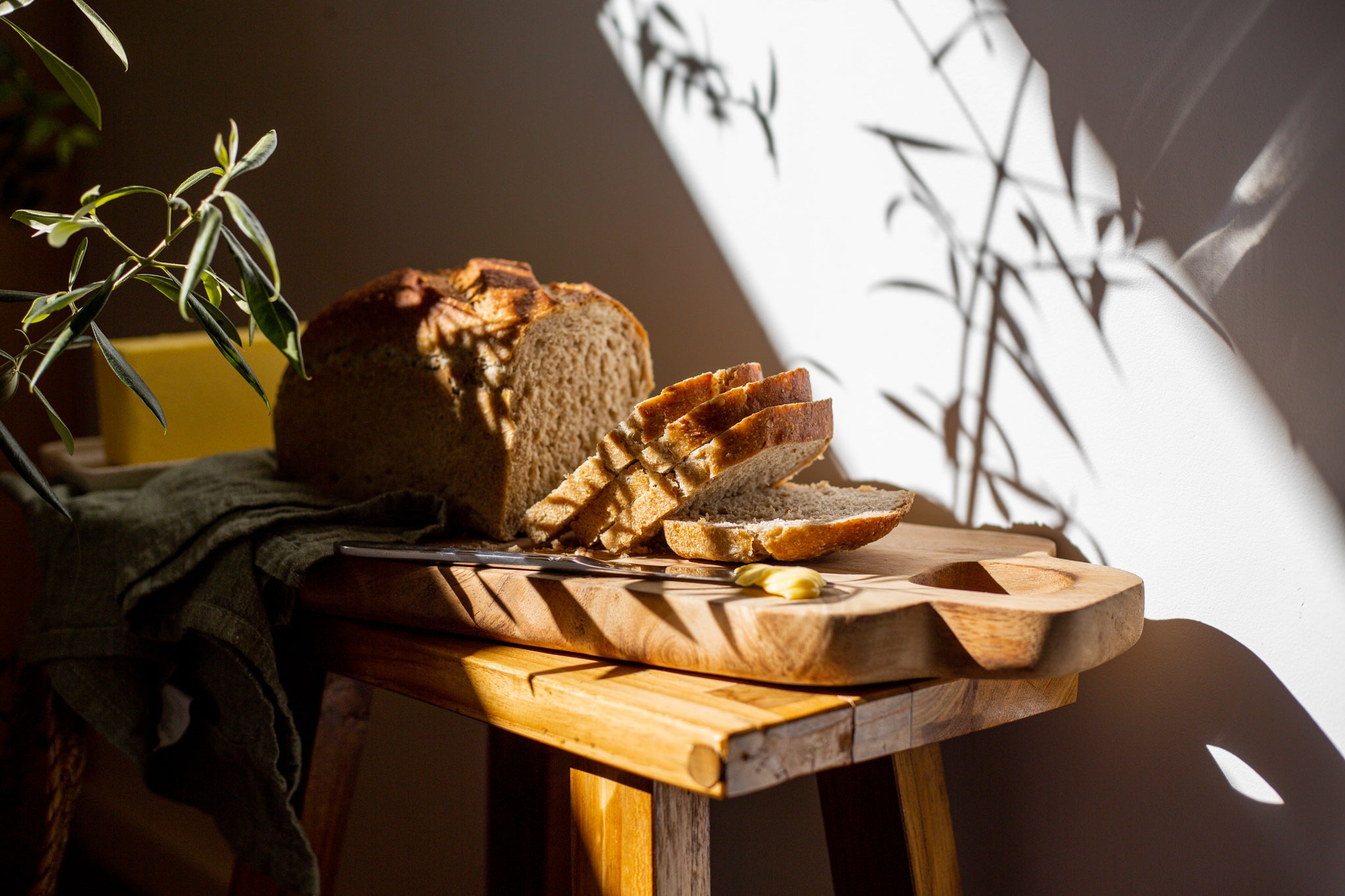 Volare sourdough loaf of bread sliced on a wooden cutting board with butter on the side