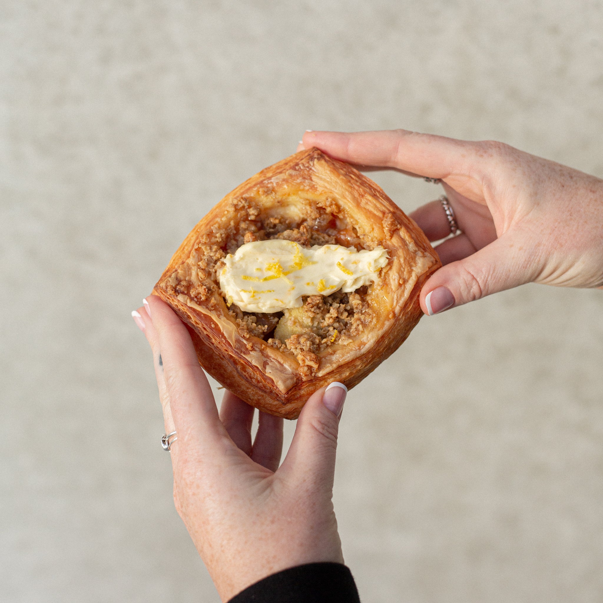 Hands holding a Volare Apple Crumble Danish