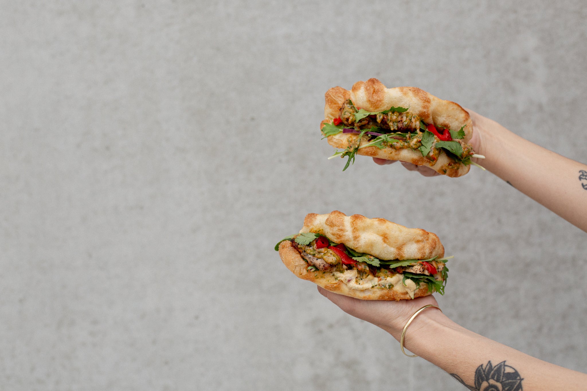 Two hands holding Chimichurri Chicken sandwiches made with Volare Focaccia Folds