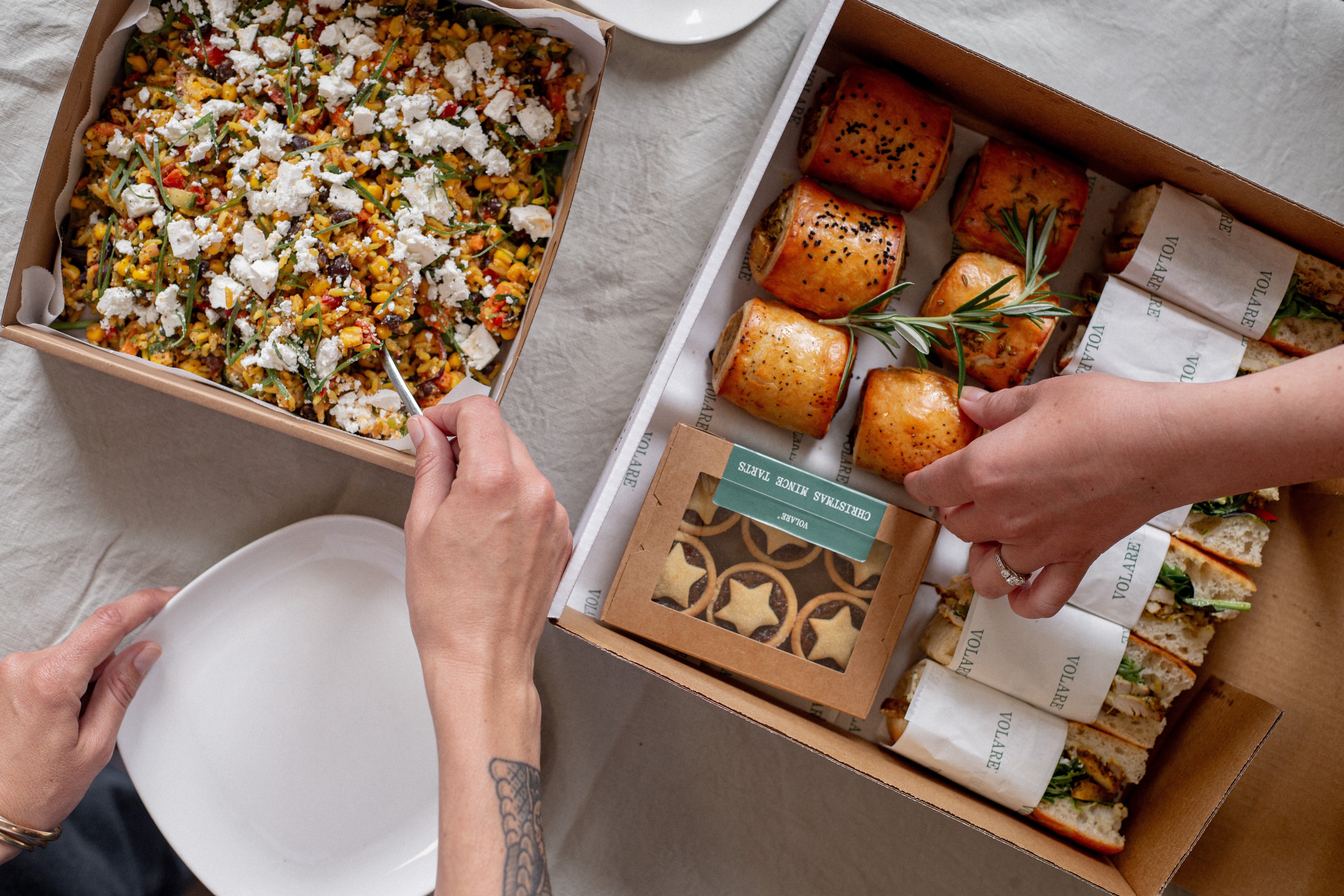 Two hands tucking into a Volare catering box