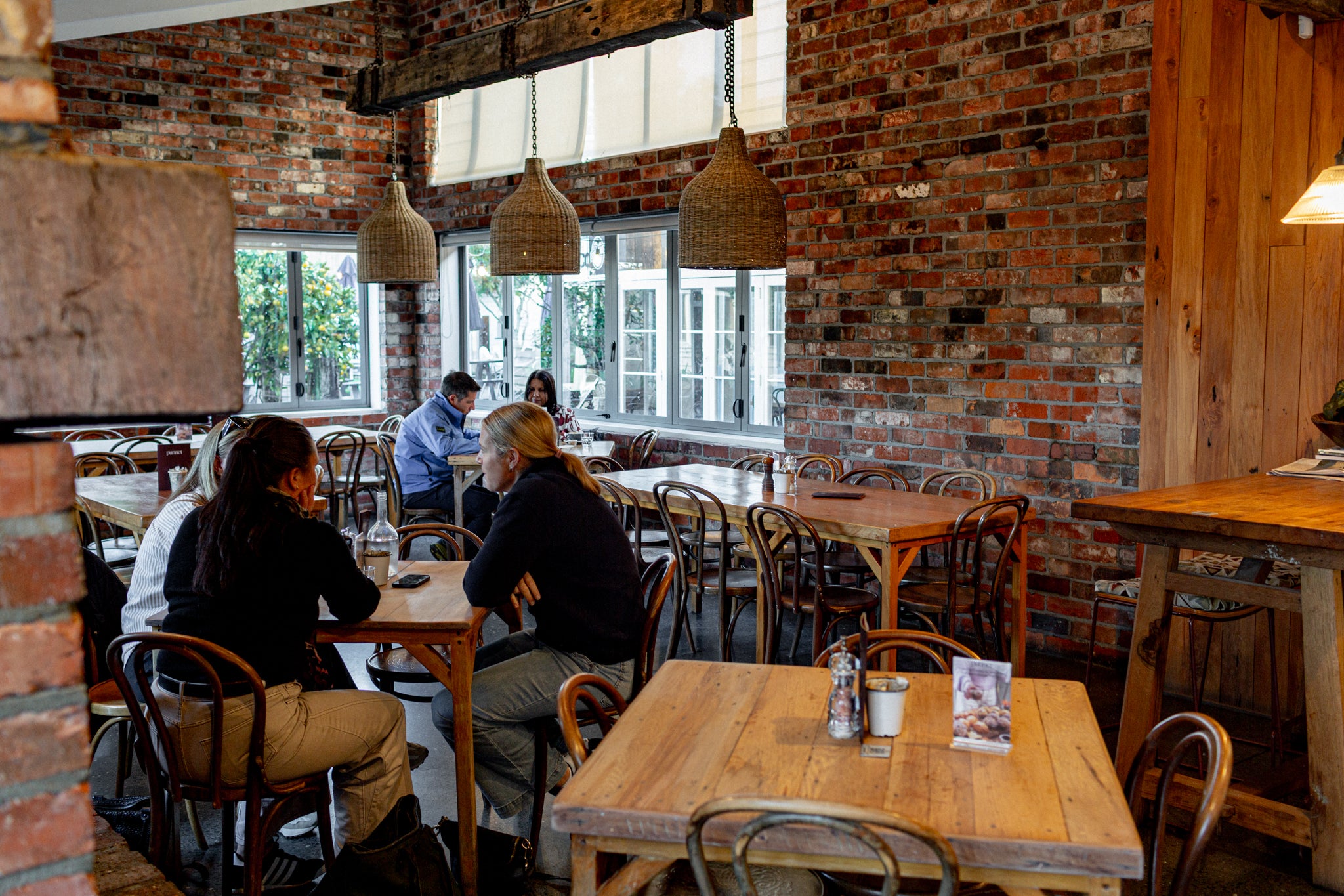 Inside Punnet Eatery with exposed brick walls, wooden tables, hanging pendant lights, and several people seated at tables.