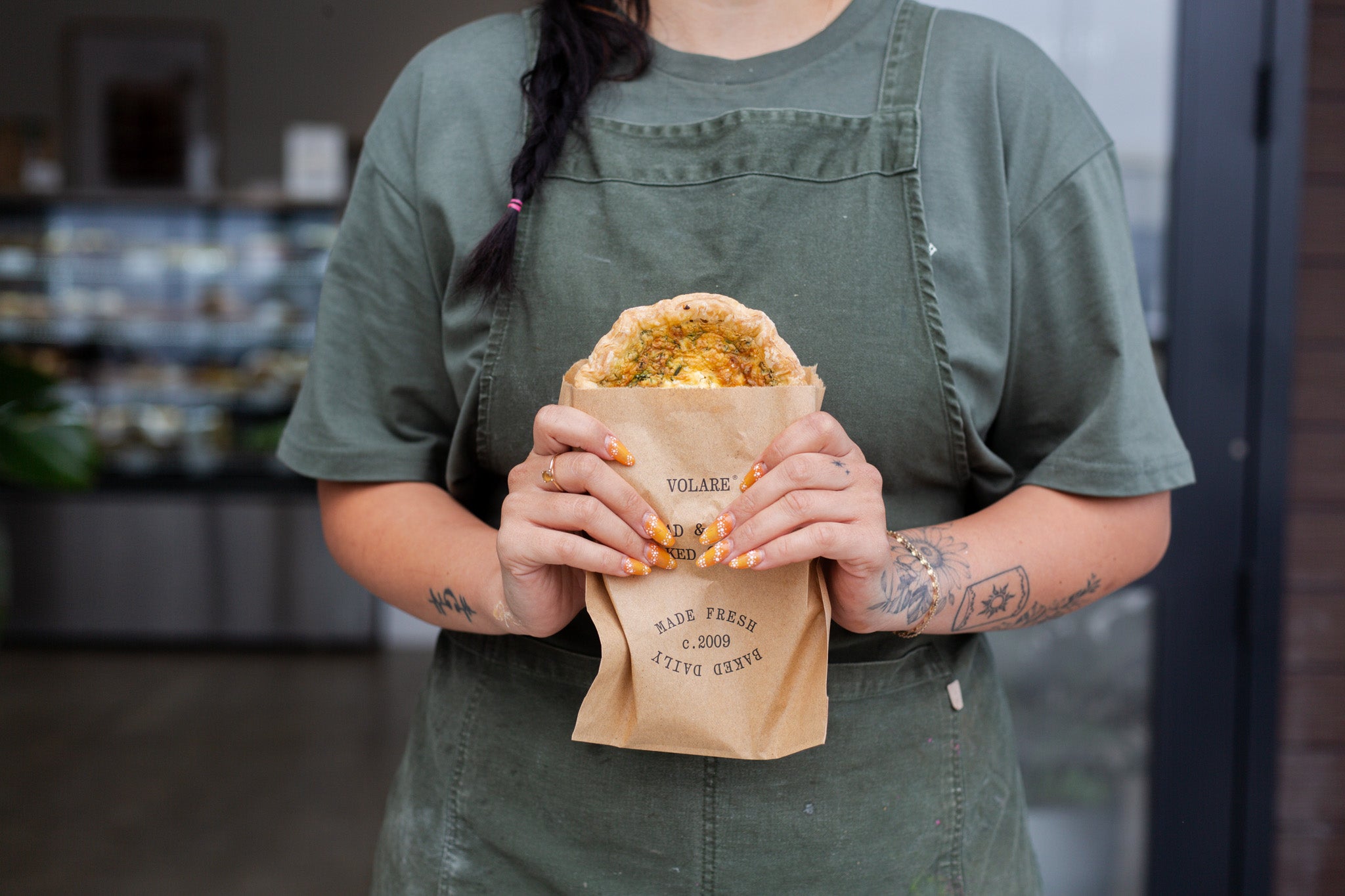 Kelly holding a paper bag with Volare quiche in it
