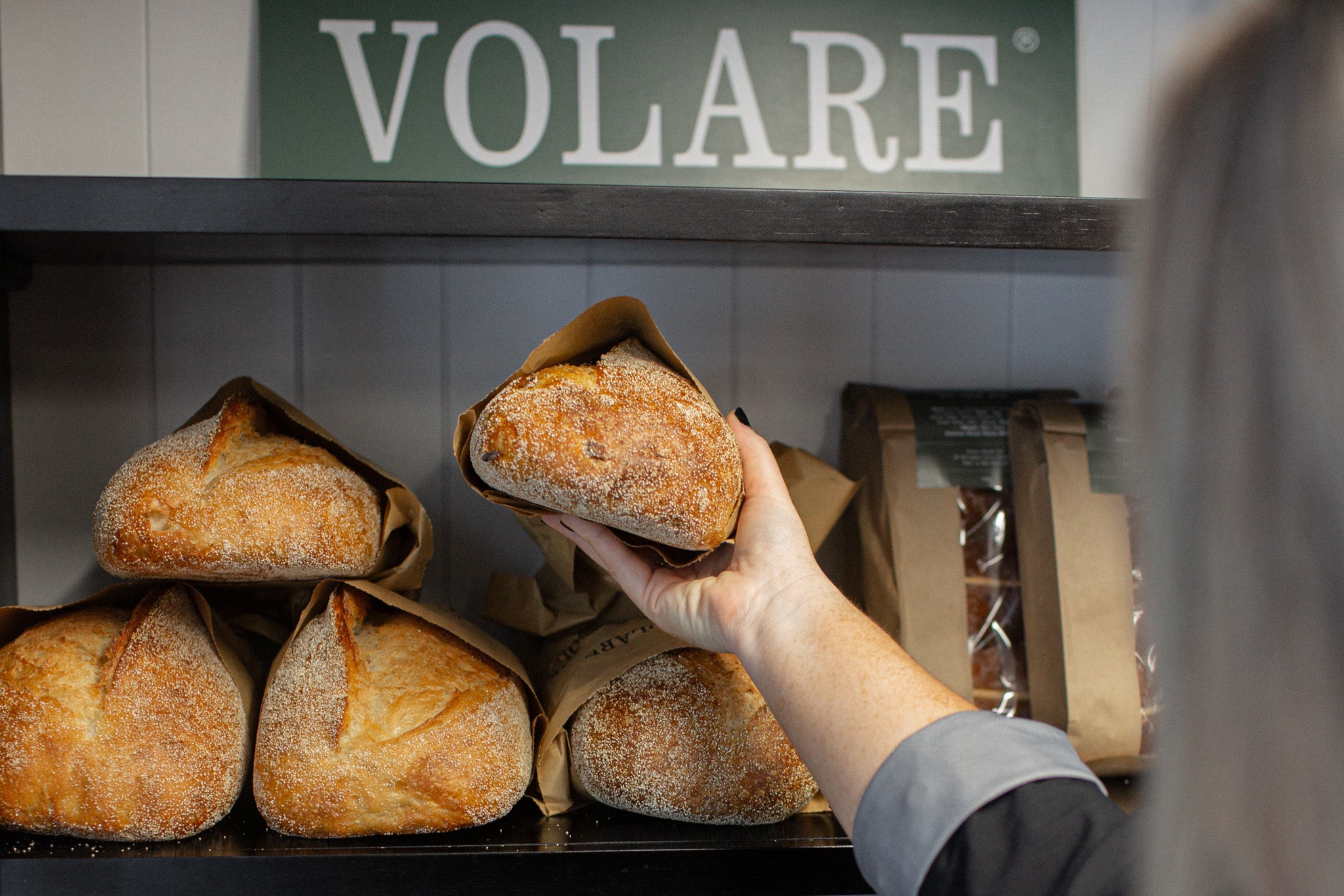 Person holding a loaf of bread in front of a display with 