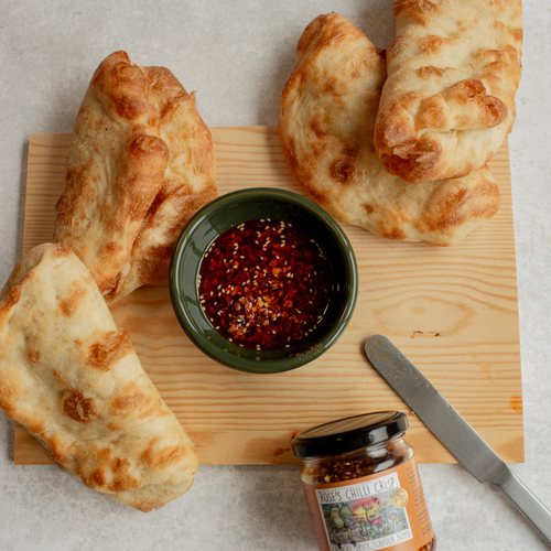 Three pieces of bread on a wooden board with a bowl of Rose
