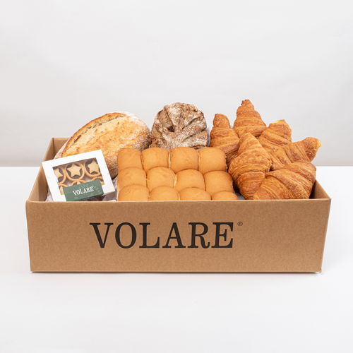 Volare bakery assortment box filled with fresh artisan breads, golden croissants, soft buns, and a pack of mini star pastries, presented in a branded cardboard delivery box.