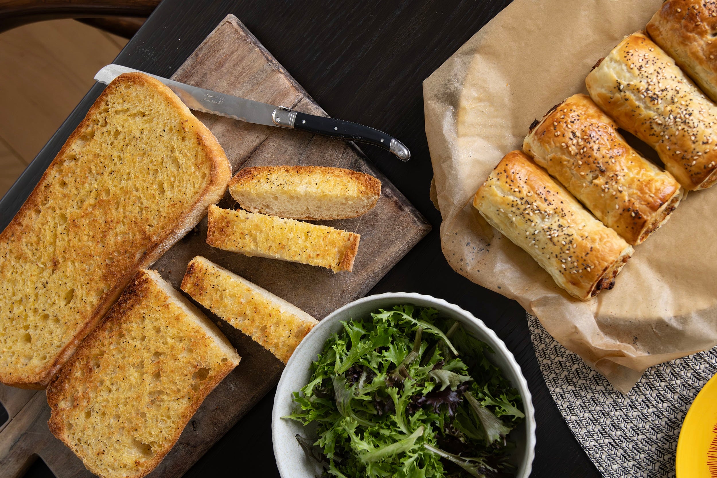 Volare frozen garlic bread and sausage rolls baked at home and spread out on a table