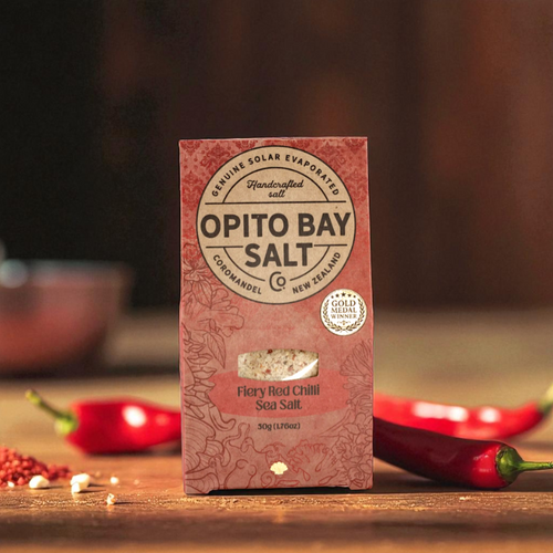 Opito Bay Salt Co. Fiery Red Chilli Sea Salt packaging with red chili peppers on a wooden surface
