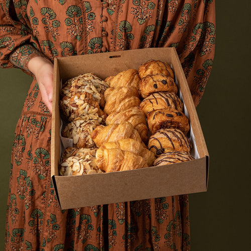 Woman holds a box of mixed mini pastries from Volare