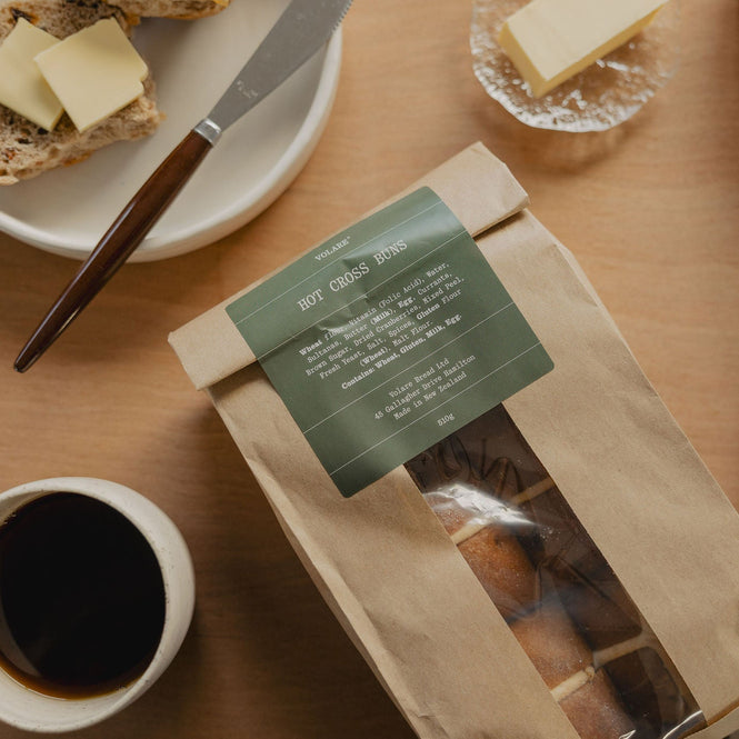 Volare Hot Cross Buns 6-Pack in Kraft packaging on a breakfast table with coffee